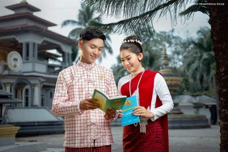 The couple in Mon traditional dress reading together beside a pagoda
