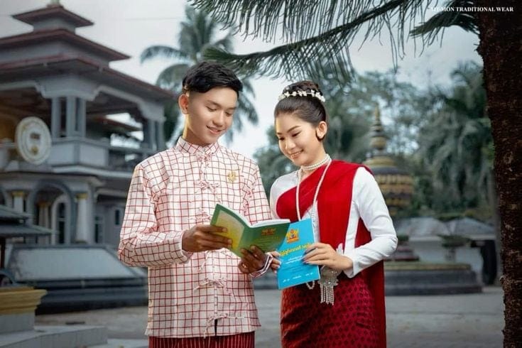 The couple in Mon traditional dress reading together beside a pagoda