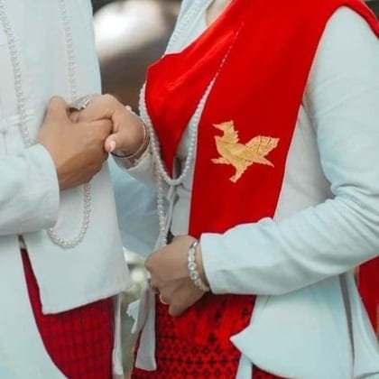 Joined hands beside the golden Hintha on the bride's red shawl