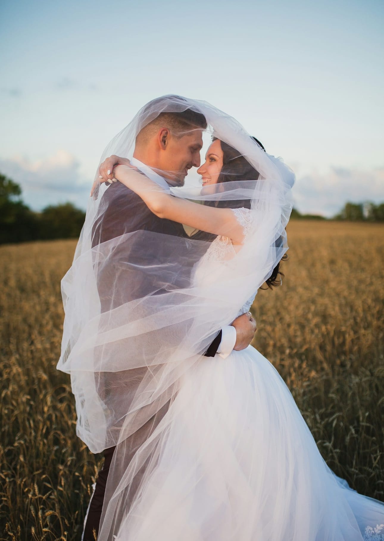 Zin Min and Yun Wati embracing beneath a flowing veil in golden evening light
